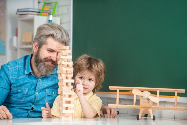 Feliz pai e filho na mesa jogando jogos de tabuleiro, aprendizagem e conceito de educação