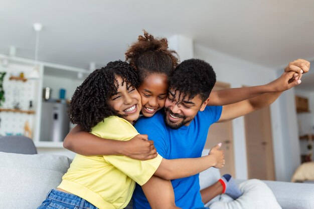 Feliz pai e mãe afro-americanos pegando carona filha orgulhosa e animada brincando de super-herói voador estendendo o braço para a frente Menina alegre montando os pais de volta jogando jogo ativo com a família em casa