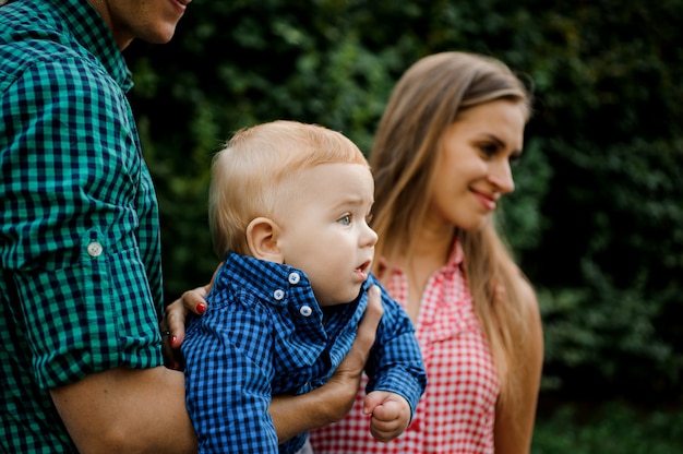 Feliz pai e mãe segurando nas mãos um menino com