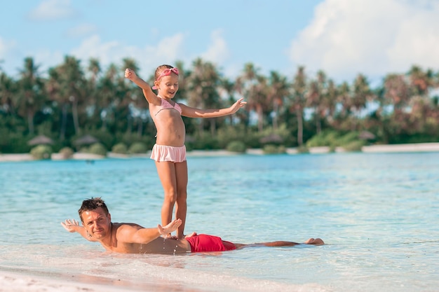 Feliz pai e sua adorável filha na praia tropical caminhando juntos