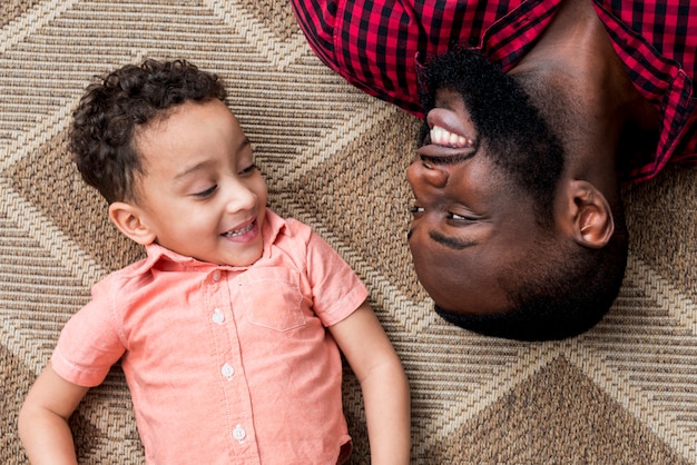 Foto feliz pai negro e filho deitado no chão