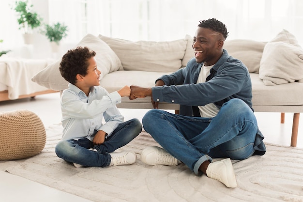 Feliz pai negro e seu filho batendo os punhos dentro de casa