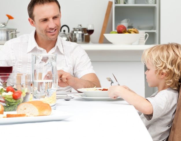 Feliz pai olhando seu filho comendo macarrão