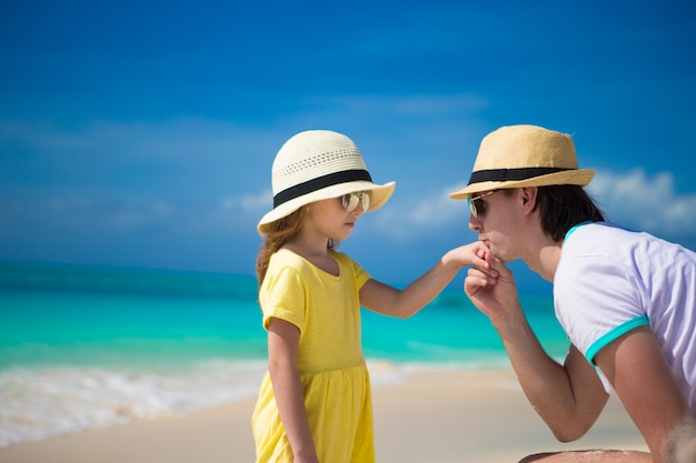 Feliz papá besa la mano de su pequeña hija en la playa