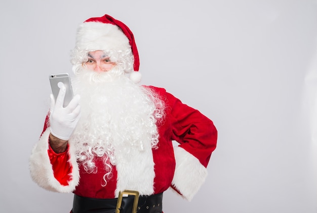 Feliz Papá Noel mirando la pantalla del teléfono móvil