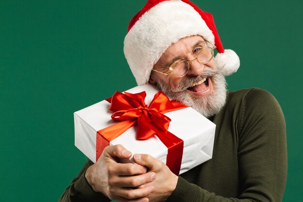 Feliz papá noel moderno barbudo que abraza el regalo