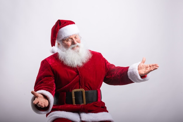 Foto feliz papá noel, sentado con los brazos abiertos en la pared blanca