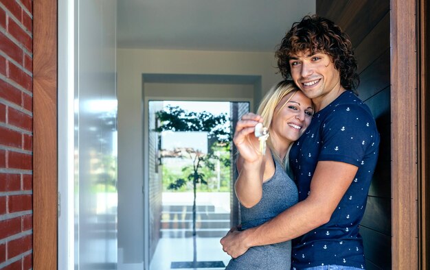 Feliz pareja abrazada mostrando las llaves de su nueva casa