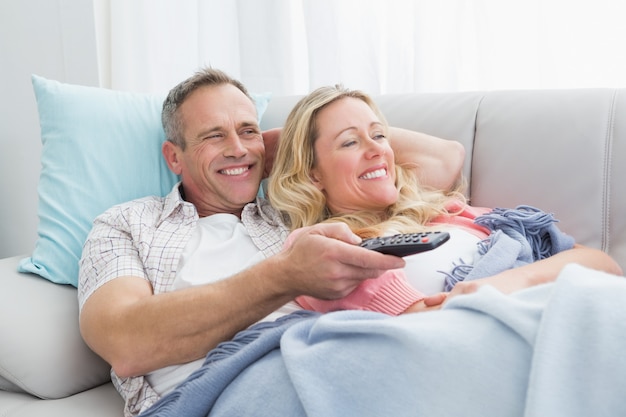 Feliz pareja abrazada en el sofá viendo la televisión