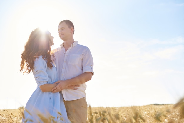 Feliz pareja abrazados en un campo de trigo