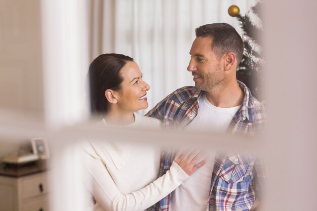 Feliz pareja abrazándose cerca del árbol de Navidad