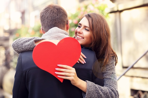 Foto feliz pareja abrazándose con corazón en la ciudad