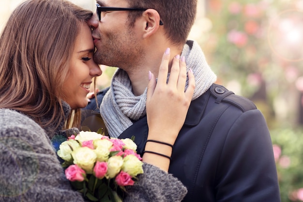 feliz pareja abrazándose con flores en la ciudad