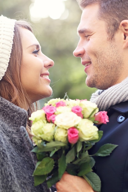 feliz pareja abrazándose con flores en la ciudad