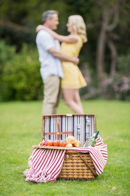 Feliz pareja abrazándose junto a la cesta de picnic afuera