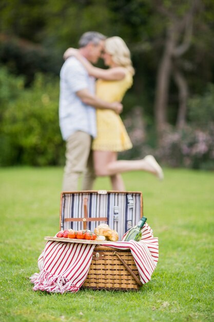 Feliz pareja abrazándose junto a la cesta de picnic afuera