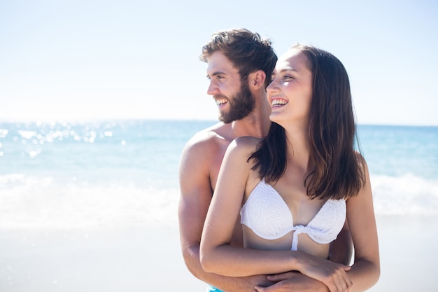 Feliz pareja abrazándose y mirando a otro lado