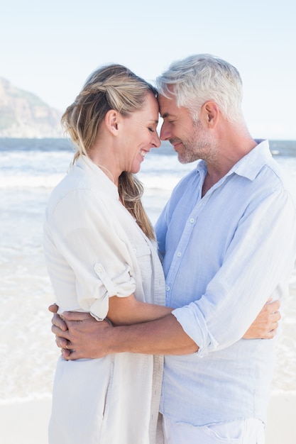 Feliz pareja abrazándose en la playa mirando el uno al otro