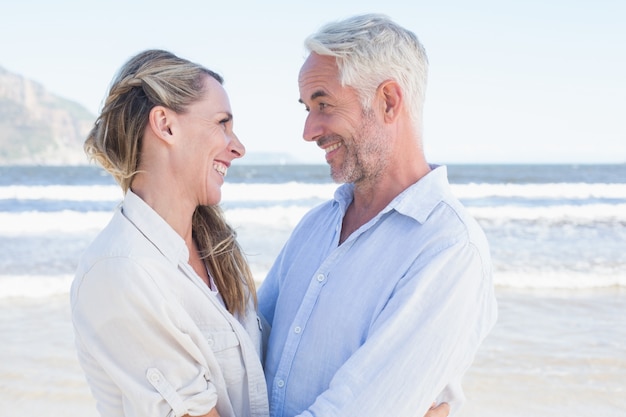 Feliz pareja abrazándose en la playa mirando el uno al otro