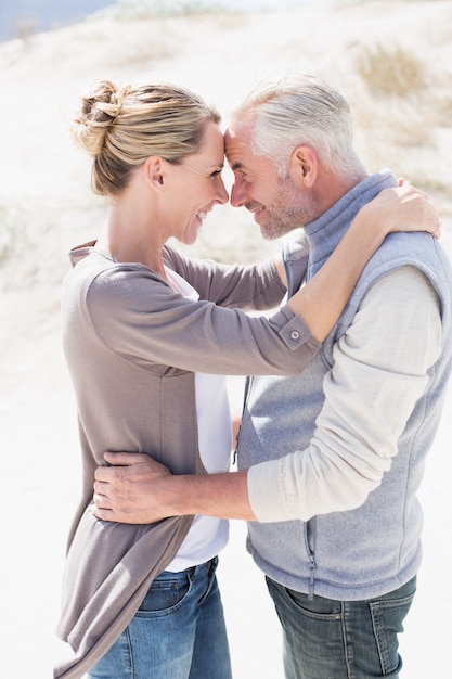 Feliz pareja abrazándose en la playa mirando el uno al otro