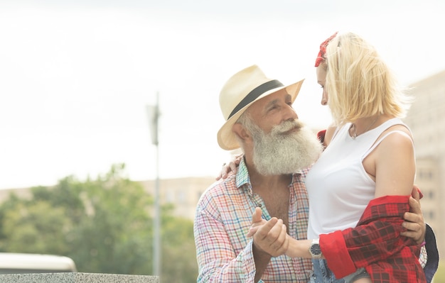 Feliz pareja abrazándose y riendo al aire libre.