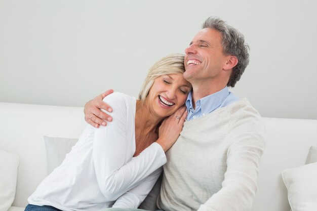 Feliz pareja abrazándose en el sofá en casa