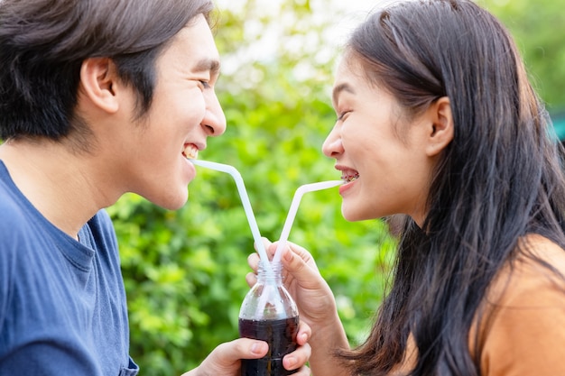 Feliz pareja abrazándose sonríe y sostiene una botella de vidrio de Cola soda en la mano,