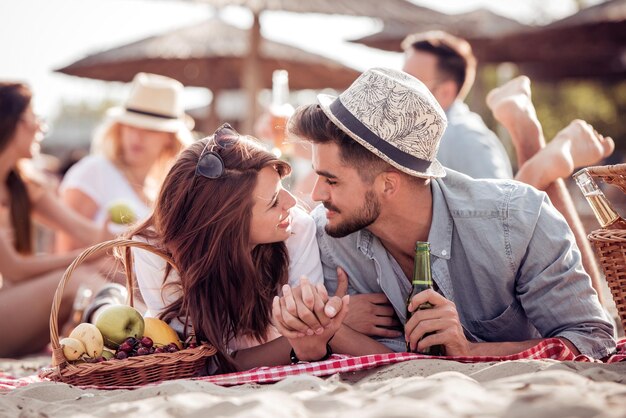 Feliz pareja acostada en una manta y besándose en la playa