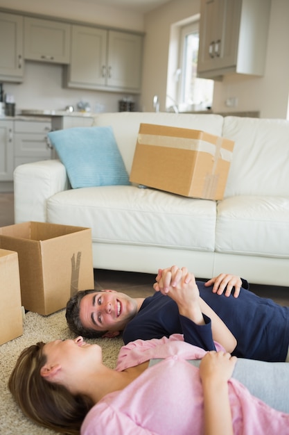 Feliz pareja acostada en el piso con cajas de mudanza