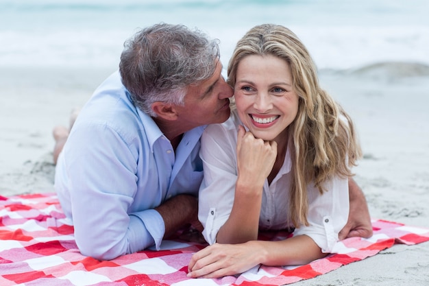 Feliz pareja acostada sobre una manta y besos