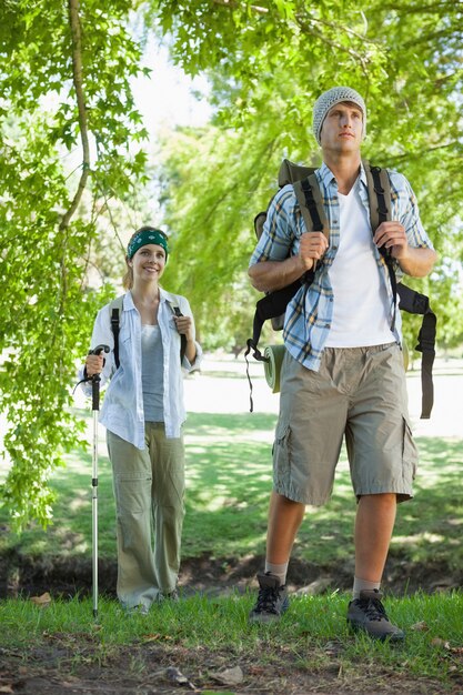 Feliz pareja activa yendo de excursión en un día soleado