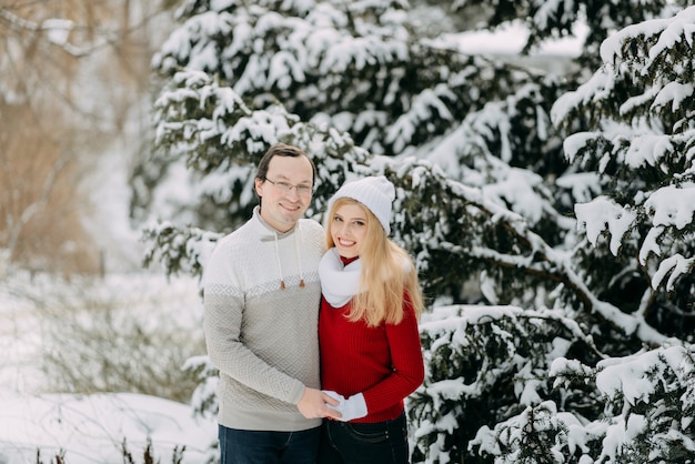 Feliz pareja adulta divirtiéndose en el bosque de invierno y sonriendo, espacio de copia