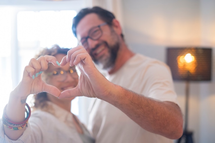 Foto feliz pareja adulta enamorada hace signo de corazón con las manos