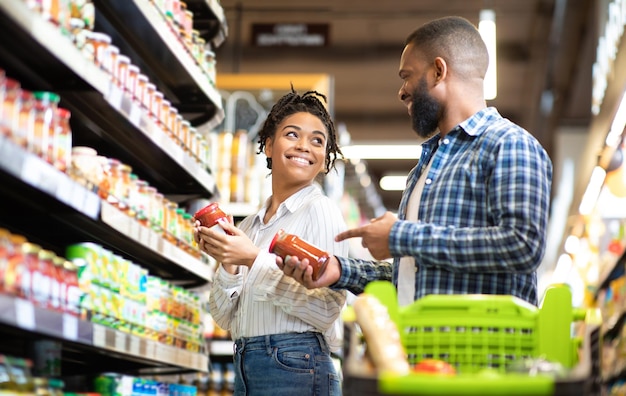 Una feliz pareja africana compra comida en el supermercado