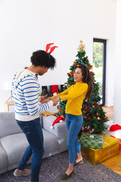 Feliz pareja afroamericana bailando junto al árbol de Navidad. Pasar tiempo de calidad juntos en Navidad.