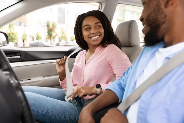 Feliz pareja afroamericana poniéndose los cinturones de seguridad