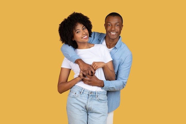 Una feliz pareja afroamericana en ropa casual abrazándose y sonriendo
