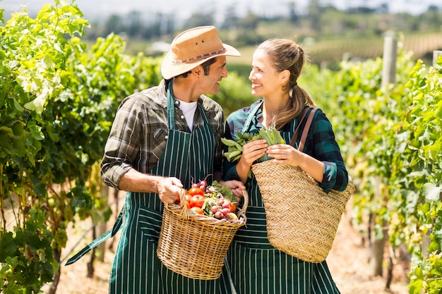 Feliz pareja de agricultores con cestas de verduras