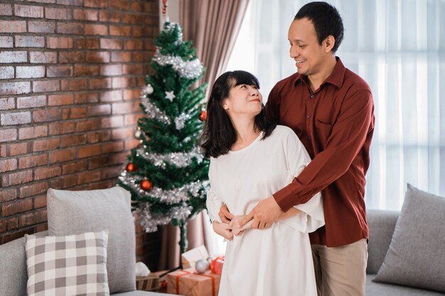 Feliz pareja amándose bailando durante el día de Navidad en casa