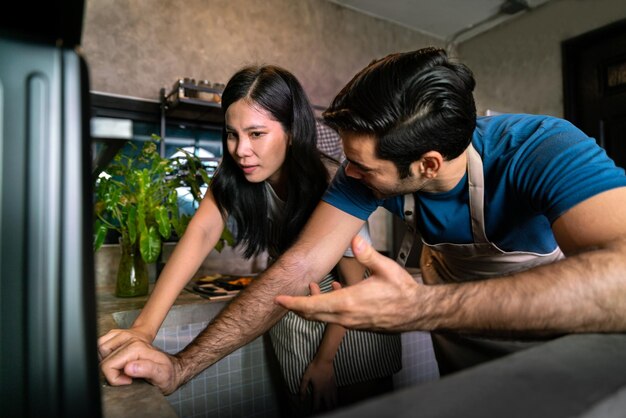 Feliz pareja de amor chef cocina masa de pizza con estufa de horno en cocina italiana para una cena especial