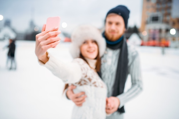 Feliz pareja de amor hace selfie en pista de patinaje
