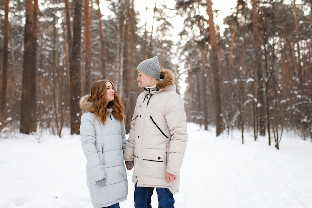 Una feliz pareja amorosa alegre camina en el bosque de invierno