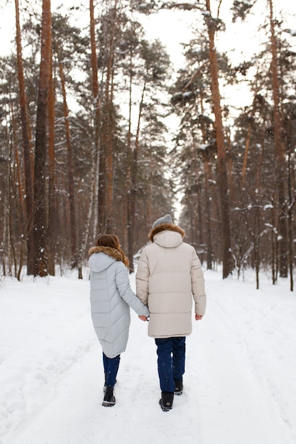 Una feliz pareja amorosa alegre camina en el bosque de invierno