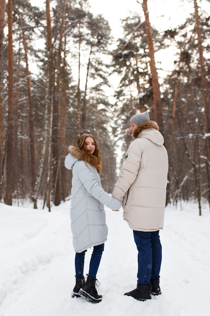 Una feliz pareja amorosa alegre camina en el bosque de invierno