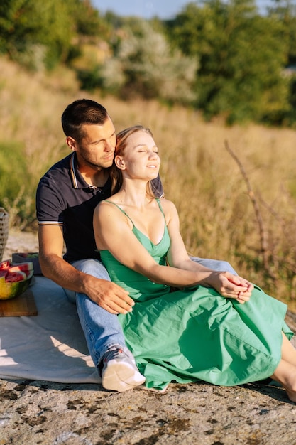 Feliz pareja amorosa besándose y teniendo una cita al aire libre pareja joven en un picnic de verano con sandía