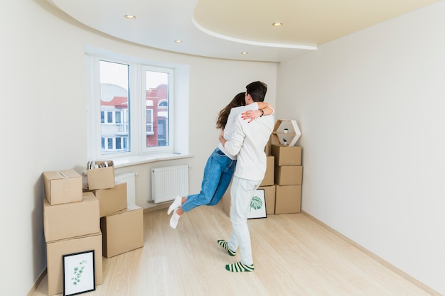 Foto feliz pareja amorosa con cajas de cartón en casa nueva en el día de mudanza