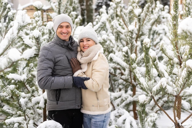 feliz pareja amorosa caminando en el bosque nevado de invierno, pasando las vacaciones de Navidad juntos. Actividades de temporada al aire libre. Captura de estilo de vida.