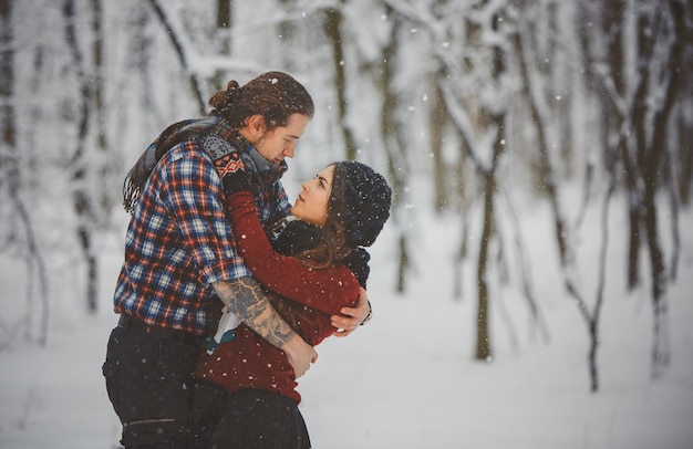 Feliz pareja amorosa caminando en bosque nevado