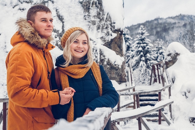 Feliz pareja amorosa caminando en el parque de invierno disfrutando de la nieve. Espacio para texto