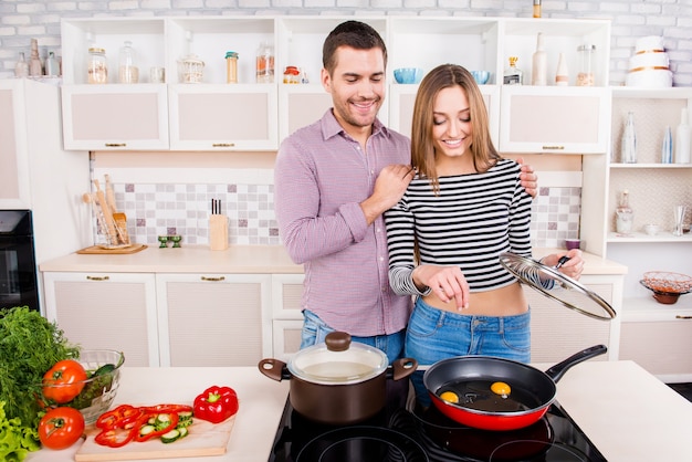 Feliz pareja amorosa cocinando en la cocina y tortilla de sal